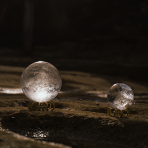Small and large Orblink Himalayan Quartz Crystal Balls displayed on stones